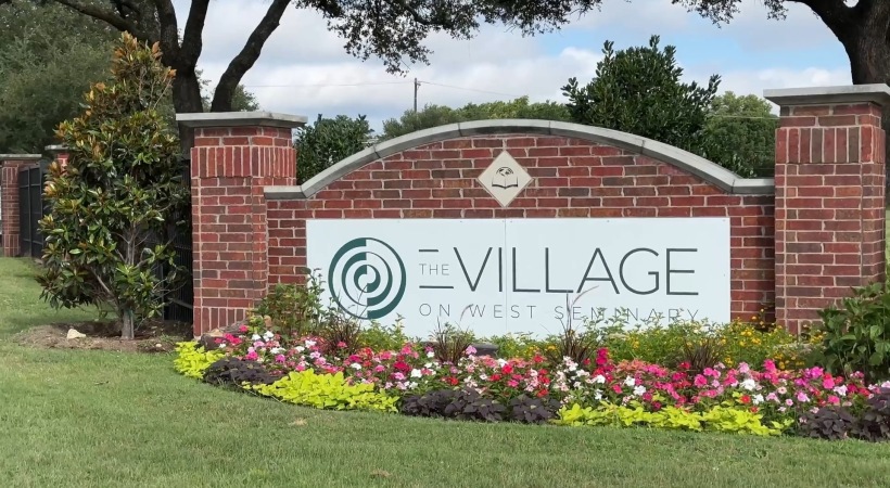 a brick sign with a flower bed in front of it