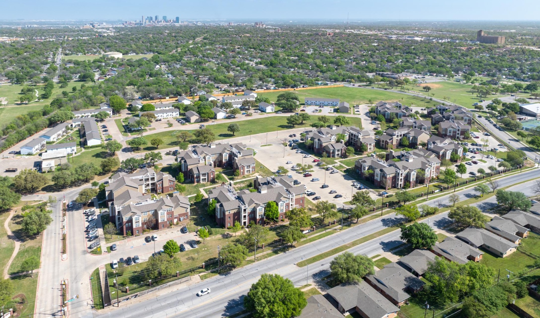 Aerial view of The Village at Waxahachie with lush greenery and a pond in the back