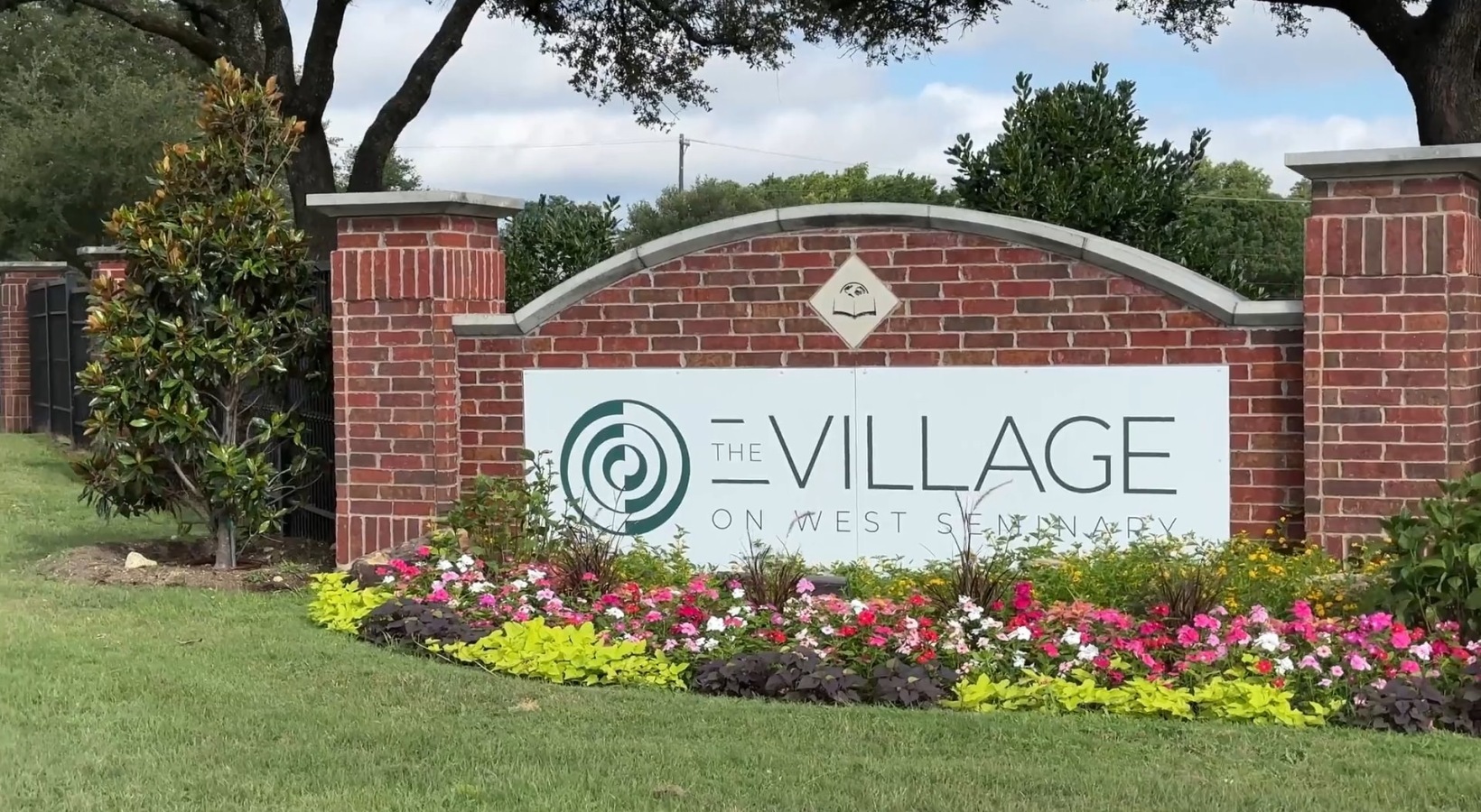 a large brick sign with a flowerbed in front of it